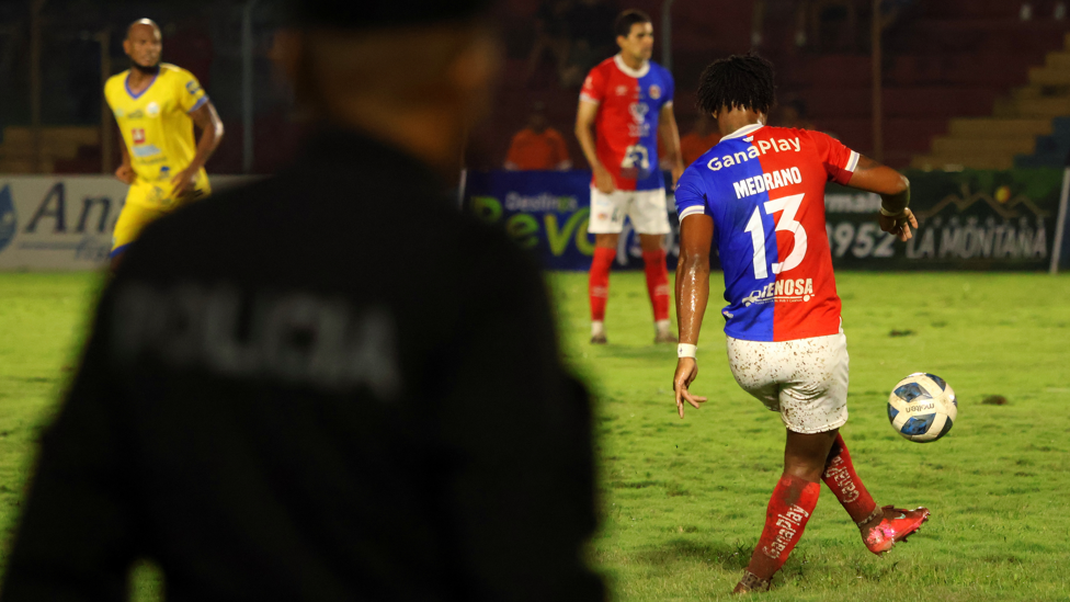 Edgar Medrano, atacante do FAS, chuta a bola de costas. Sua camisa mostra o número 13 com seu sobrenome, no Estádio Óscar Alberto Quiteño em 11 de outubro de 2025, durante o jogo entre o time local FAS e o Municipal Limeño, em Santa Ana, El Salvador.