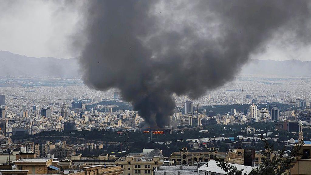 Asap mengepul setelah Israel dilaporkan menyerang suatu gedung yang digunakan oleh media pemerintah Iran di Teheran, pada 16 Juni 2025.