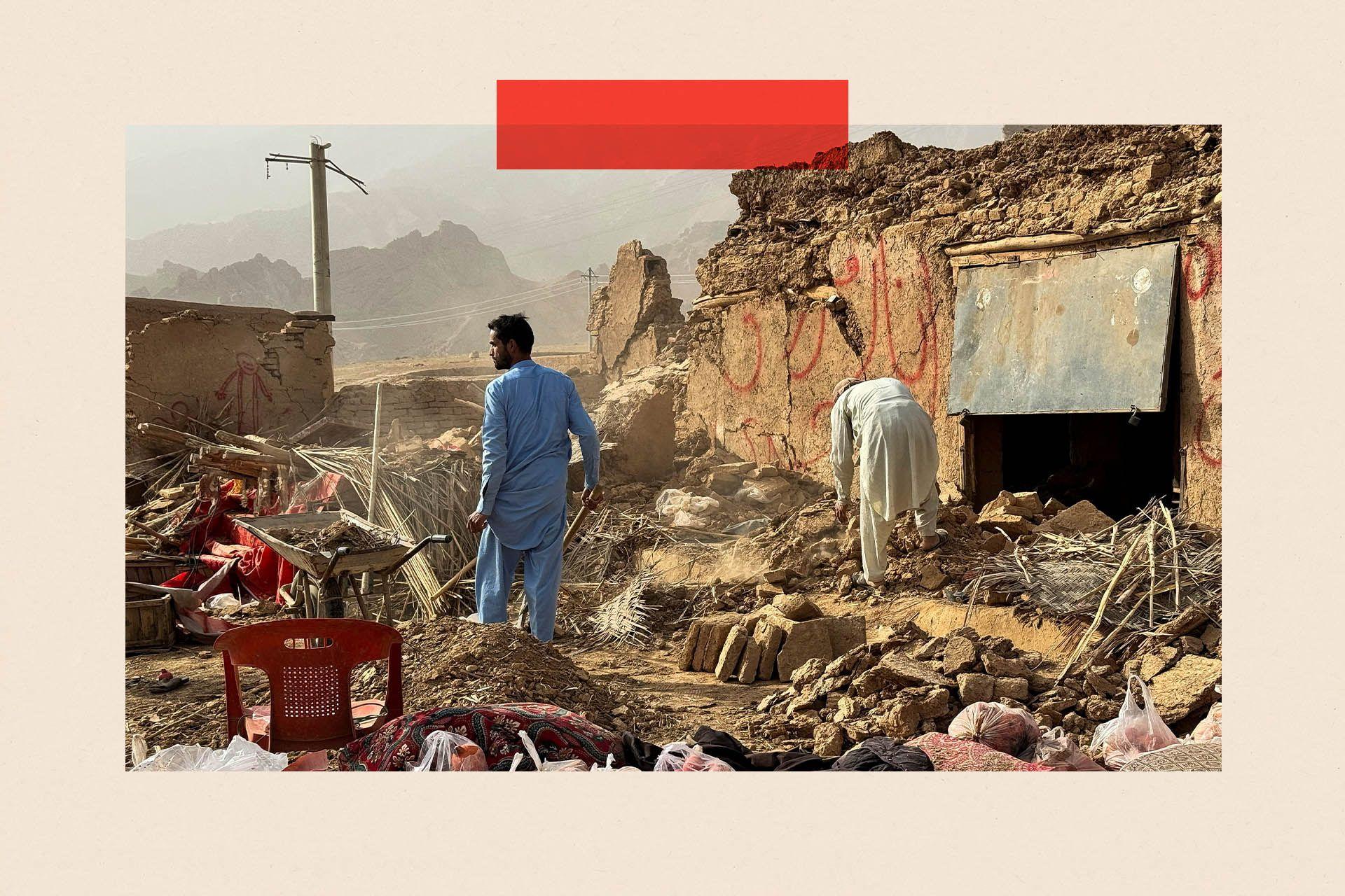 Un hombre con túnica y pantalones azules inspecciona los daños causados por un terremoto. Está de pie entre los escombros de una casa, mirando hacia las montañas en la distancia. Otra figura a la derecha se inclina sobre