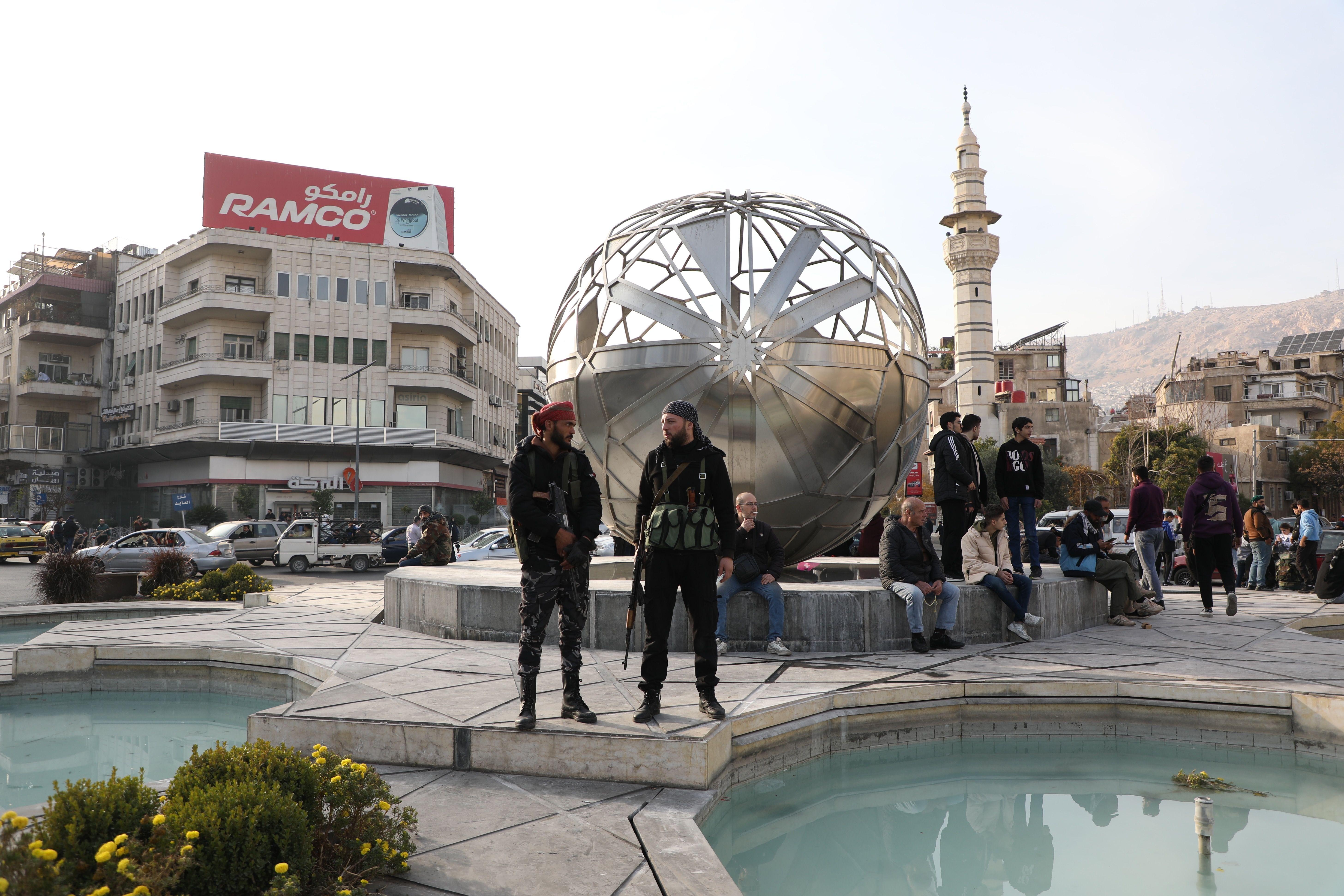 رجال مسلحون يقفون في الساحة خارج البنك المركزي السوري في اليوم التالي لسقوط النظام