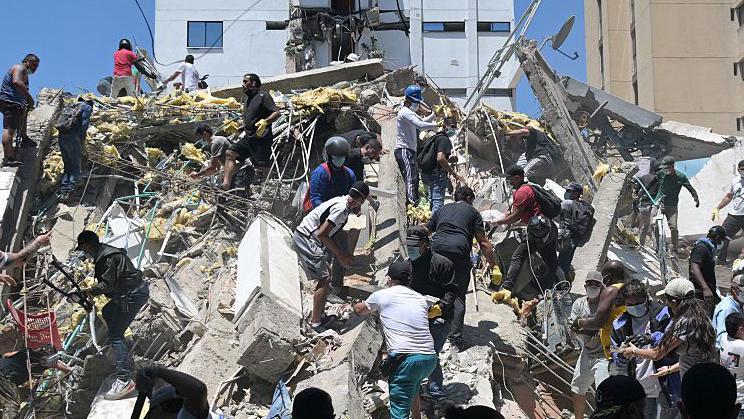 Personas buscan sobrevivientes entre los escombros de un edificio derrumbado tras un terremoto en Cali.