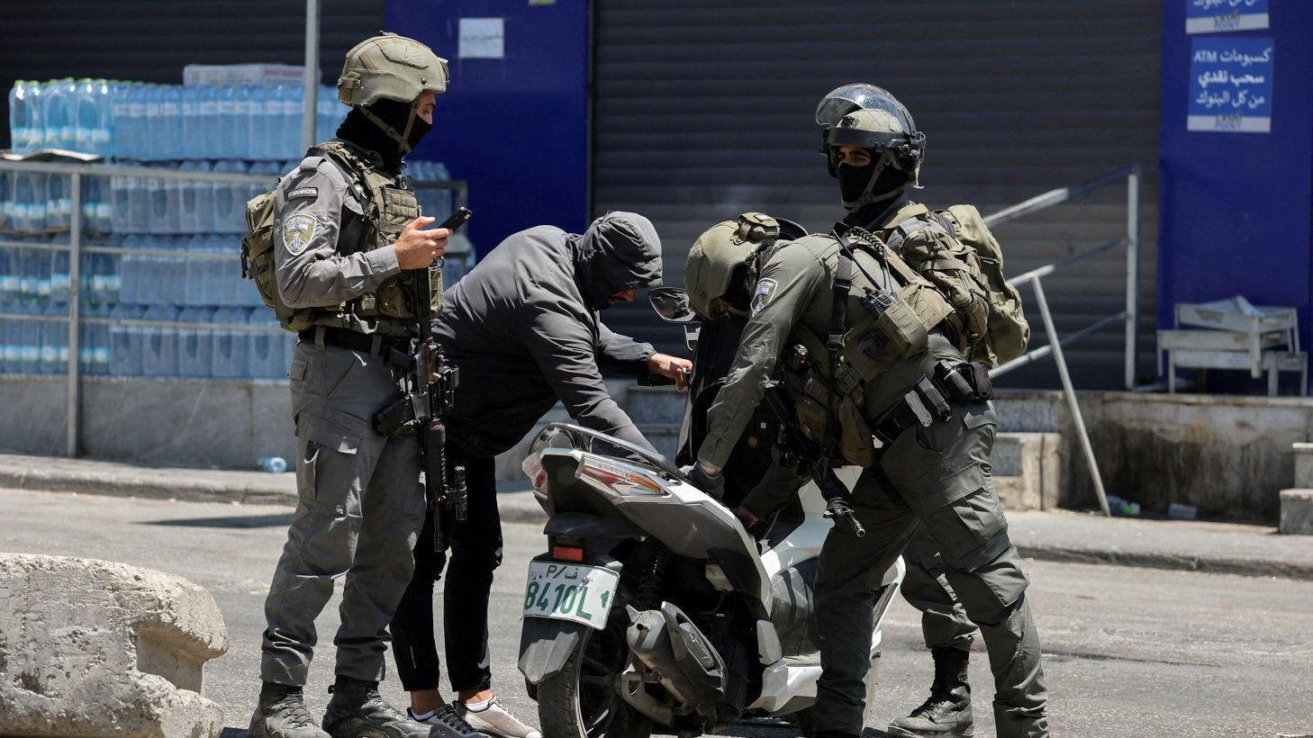 القوات الإسرائيلية تفحص دراجة نارية فلسطينية في مخيم قلنديا للاجئين بالضفة الغربية التي تحتلها إسرائيل