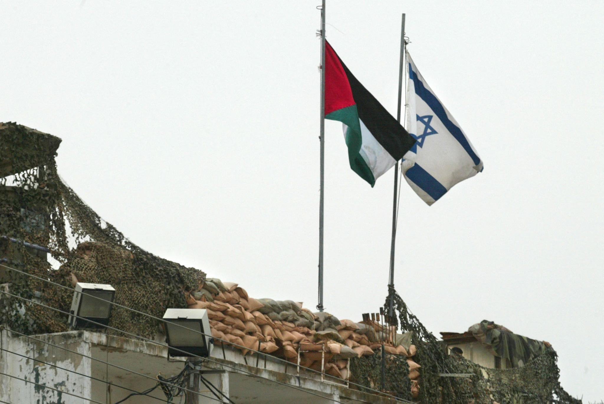 الصراع العربي الإسرائيلي: ما هي حدود 1967؟ وما هو حل الدولتين؟ 7 علمان فلسطيني وإسرائيلي عند نقطة تفتيش بيت جالا في الضفة الغربية المحتلة، في 19 مارس/آذار 2002