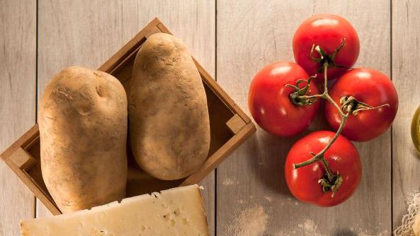 Papas y tomates sobre una mesa de madera