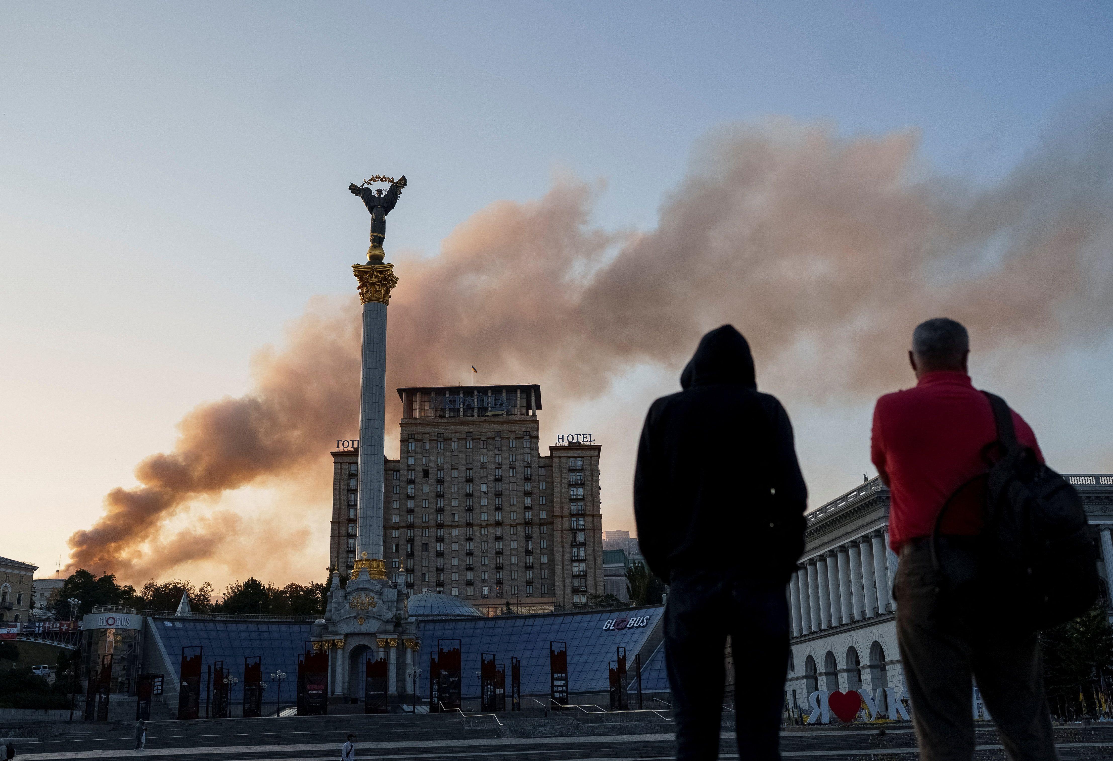 Unos hombres ven la columna de humo que sale del edificio del Gabinete.