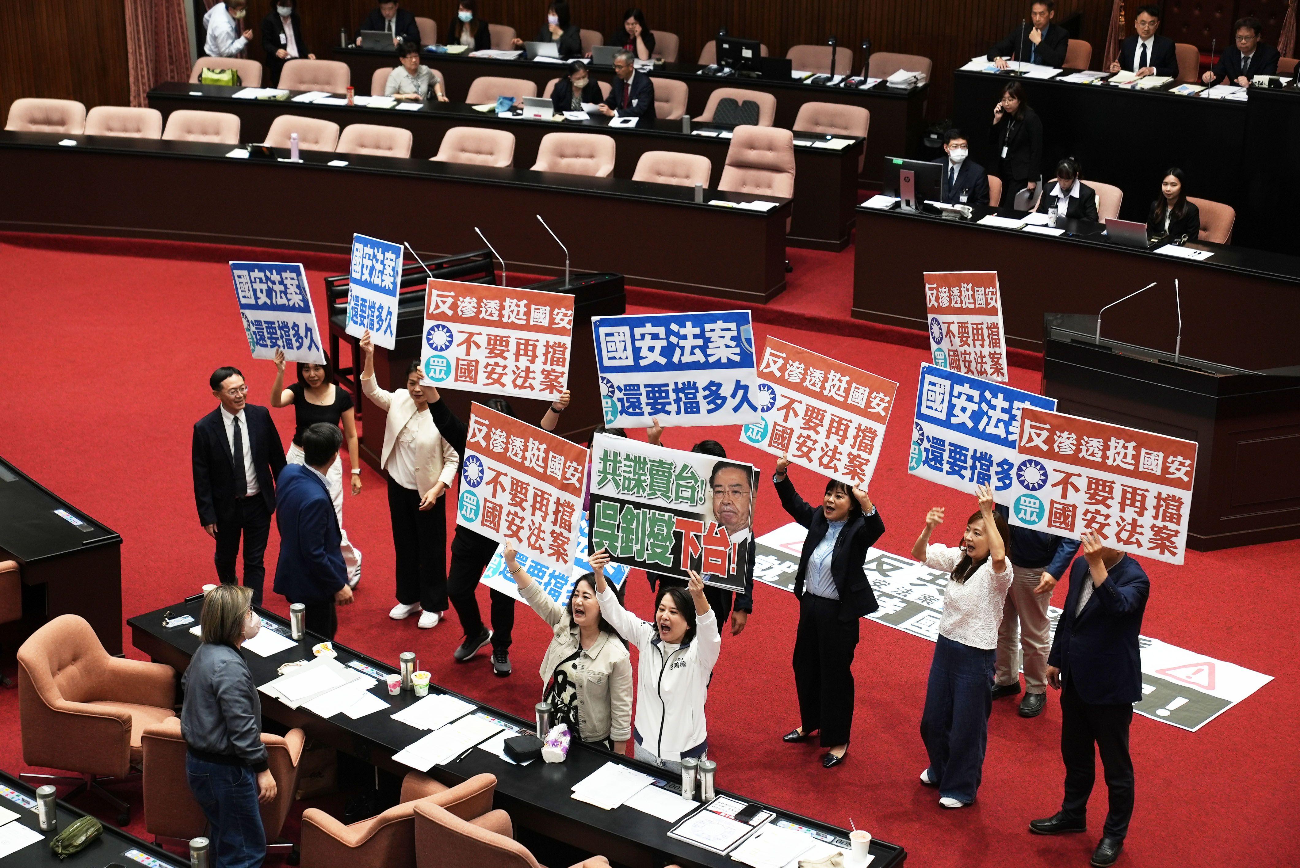 一批人士在台灣立法會的會議廳中央站立，並舉起一些示威紙牌，部份紙牌寫有「國案惡法，還要擋多久」等字眼。