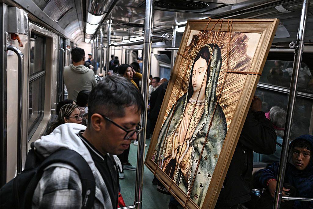 Un hombre viaja en el Metro de Ciudad de México y frente a él un cuadro de la Virgen de Guadalupe.