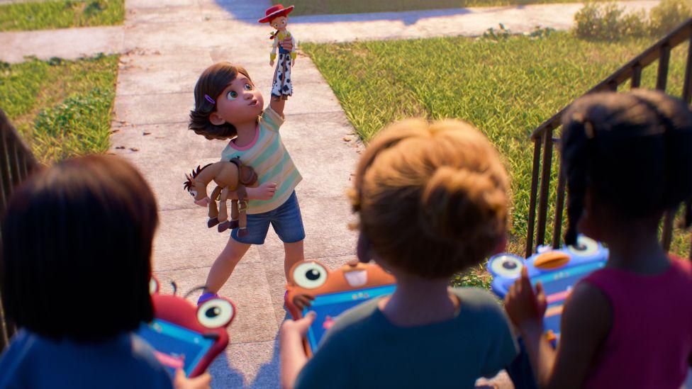 Bonnie Anderson, la niña de "Toy Story", sostiene en alto sus juguetes favoritos, Jessie y Bullseye, mientras sus amigos juegan con sus tabletas.