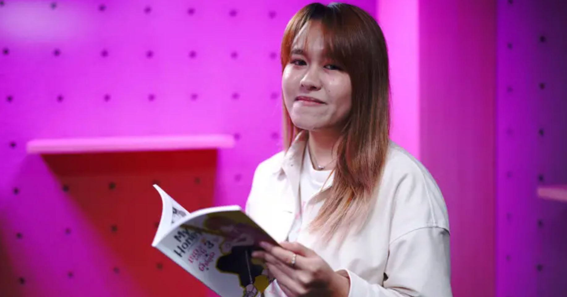 身穿白襯衫的拉努卡·宋芒一邊看漫畫書一邊對著鏡頭微笑。