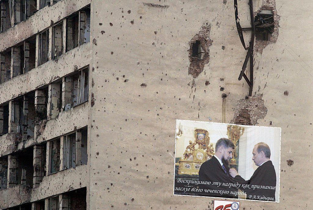 Плакат із зображенням Володимира Путіна, який вручає нагороду Рамзану Кадирову, на пошкодженій у боях стіні в центрі Грозного, 28 листопада 2005 року