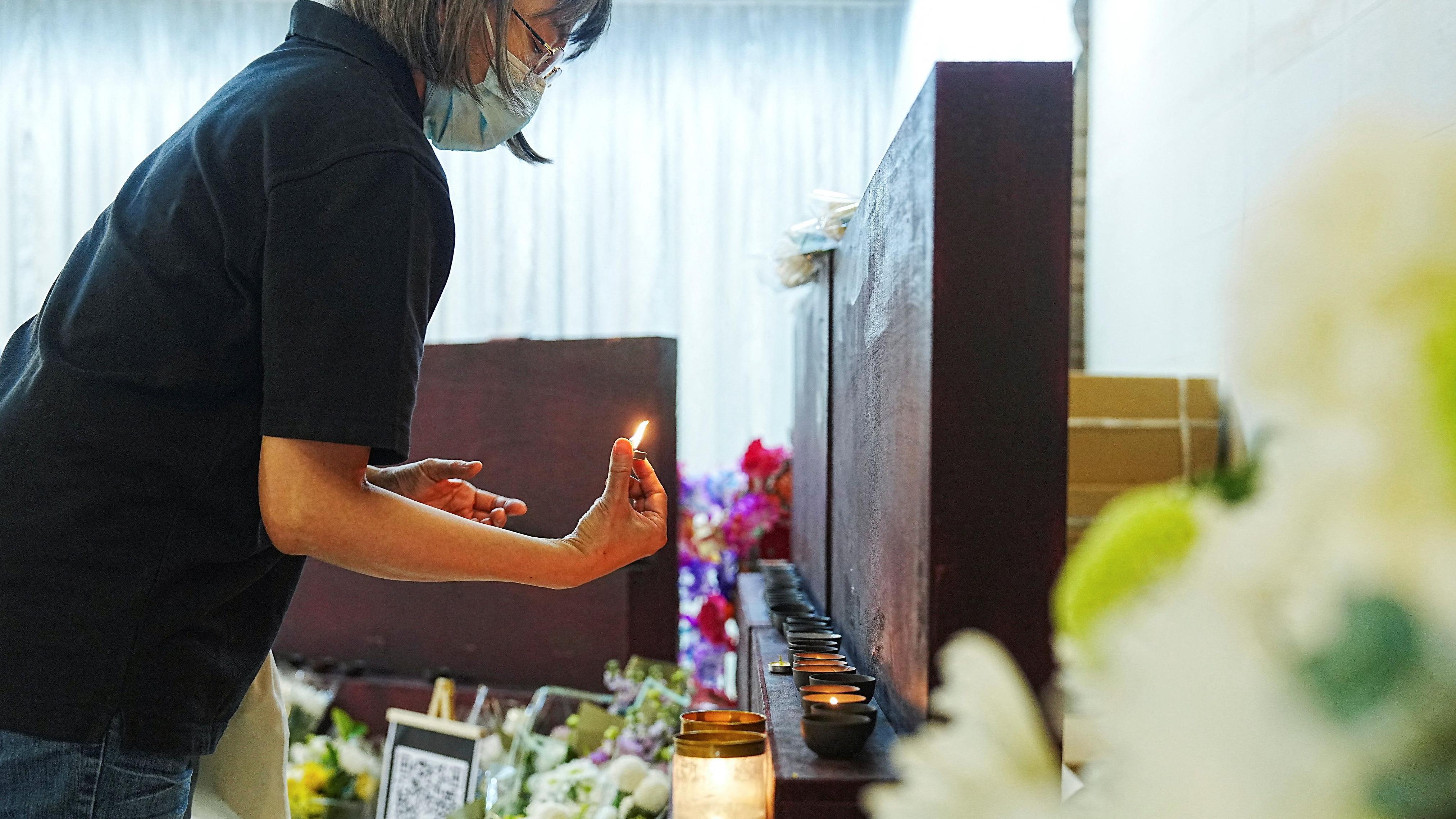 2025年12月2日，一名女子在九龍殯儀館點燃蠟燭，悼念香港大埔宏福苑火災中的罹難者。