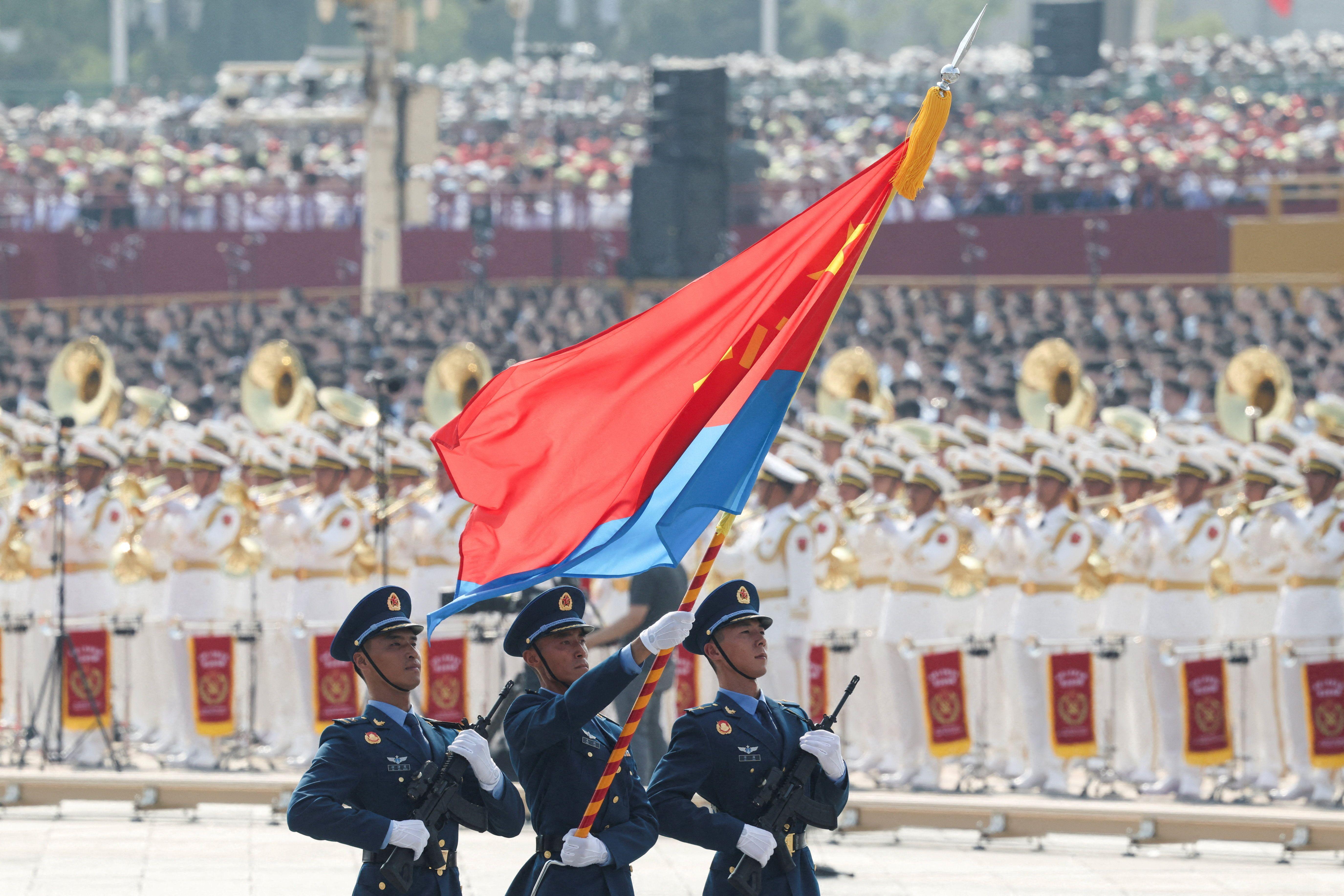 三名中國人民解放軍官兵護衛著軍旗前進。