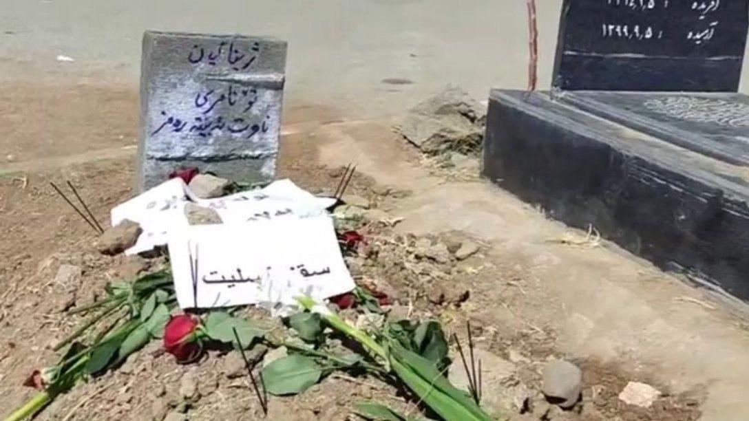  قبر مهسا جينا أميني، عليه بعض الورود ويظهر عليه كلام مكتوب بخط اليد يقول "اسمك أصبح رمزاً".