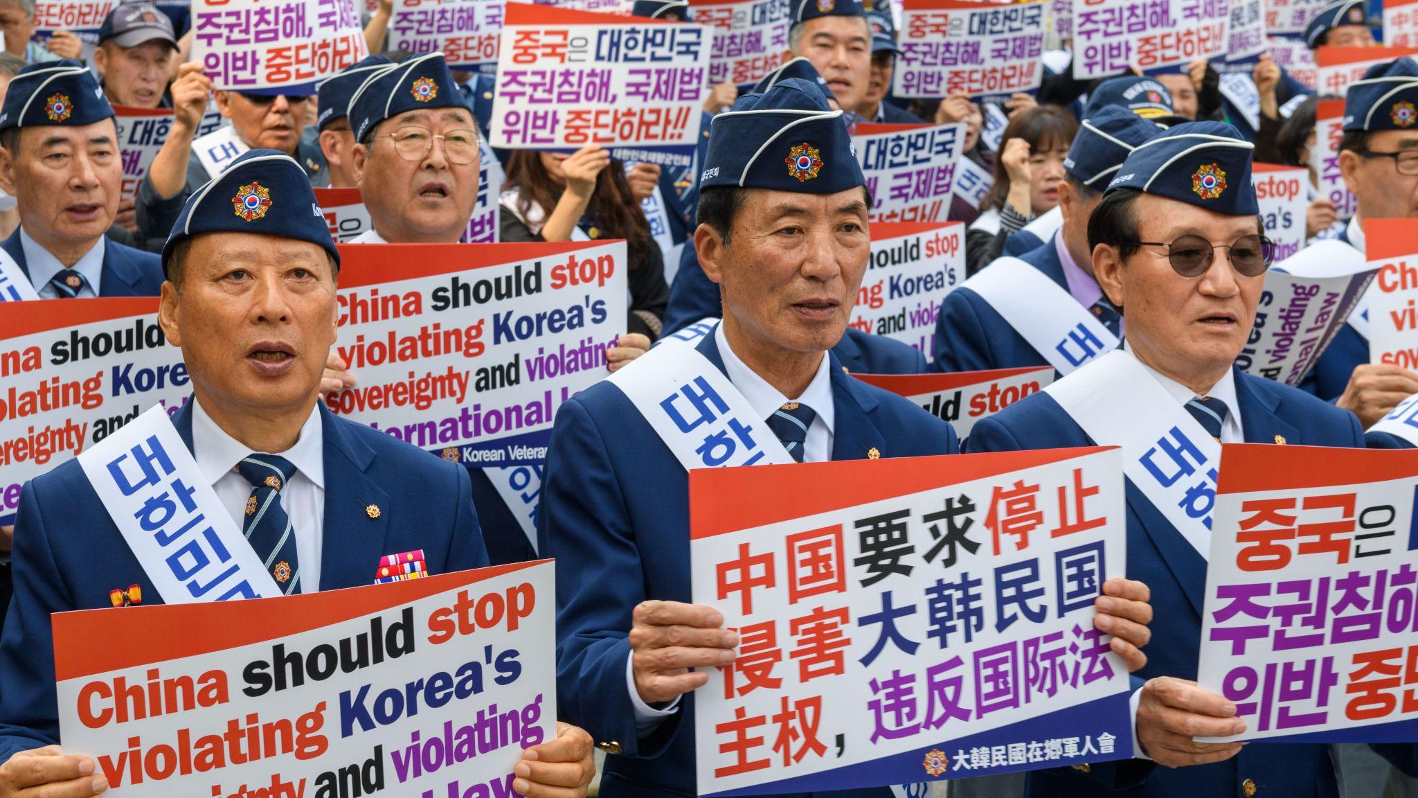 首爾明洞中國駐韓國大使館外一群「韓國在鄉軍人會」老兵舉起中、英、韓文標語抗議中國在黃海爭議水域架設構築物(30/4/2025)