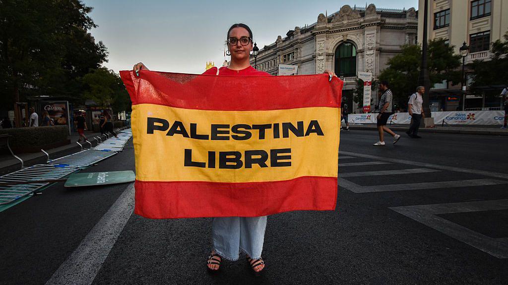 Una mujer con una bandera de España en la que pone Palestina libre.