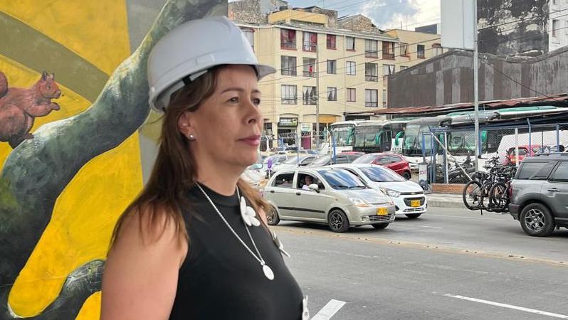 Mujer con un casco blanco en la cabeza en la calle. Autos en el fondo.