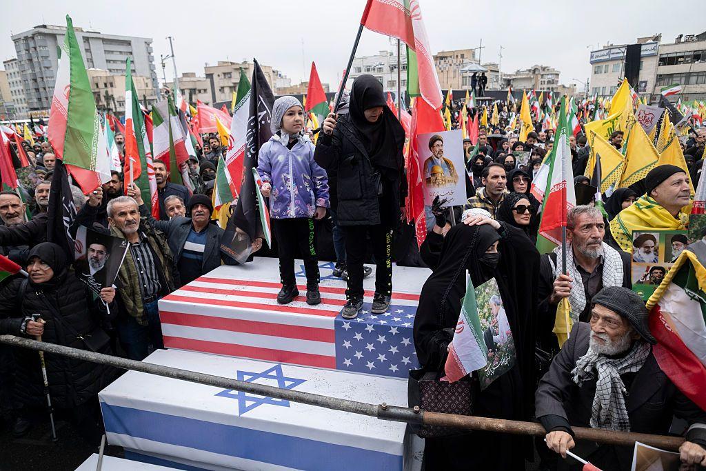 Niños iraníes se ponen de pie sobre ataúdes que simbolizan los de soldados estadounidenses e israelíes, mientras participan en una manifestación para conmemorar el Día Internacional de Al-Quds —también conocido como el Día de Jerusalén— en Teherán, Irán, el 13 de marzo de 2026.