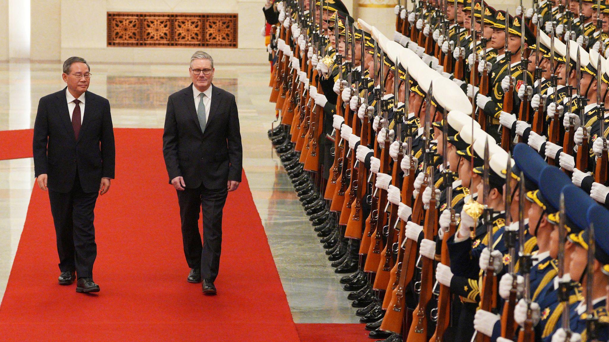 北京人民大會堂內，中國總理李強（左）陪同施紀賢爵士（中）檢閱中國解放軍儀仗隊（29/1/2026）