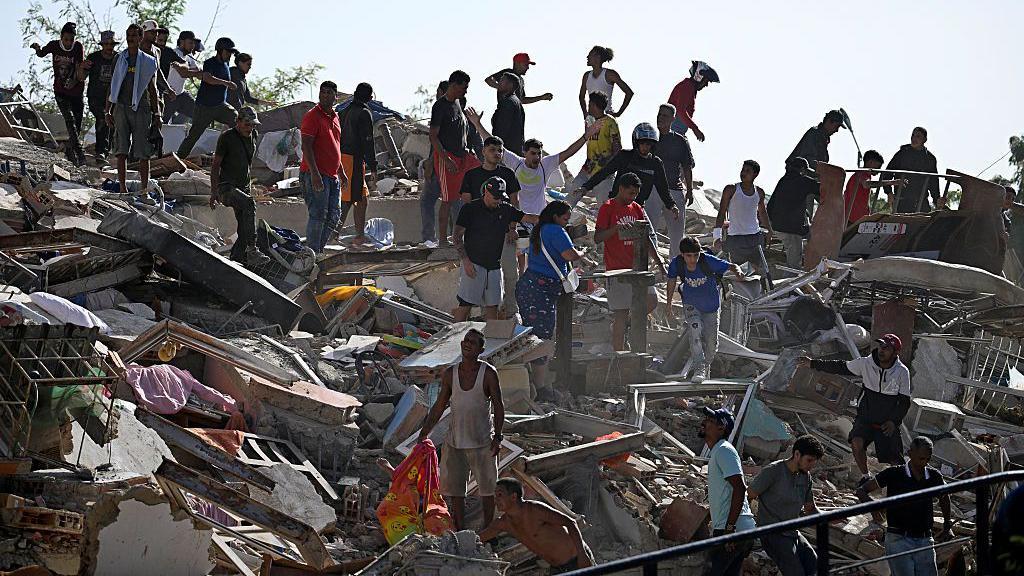 Personas buscan supervivientes mientras otras intentan rescatar pertenencias de un edificio colapsado tras un terremoto en Catia La Mar, estado de La Guaira, el 25 de junio de 2026.