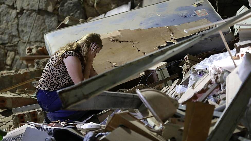 Una mujer se agarra la cabeza en medio de los escombros de una casa destruida por los sismos 