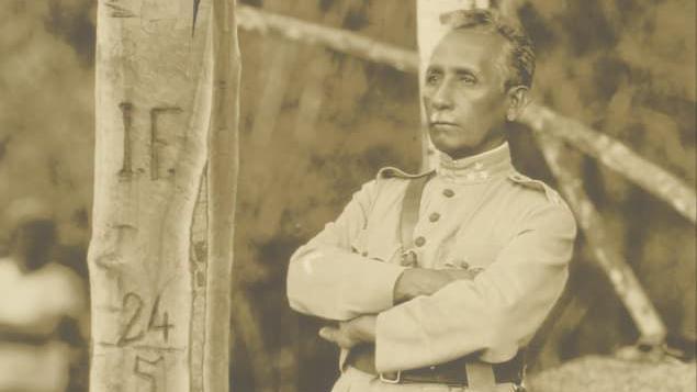 Foto em s&eacute;pia mostra Rondon de bra&ccedil;os cruzados olhando para o horizonte ao lado de uma &aacute;rvore