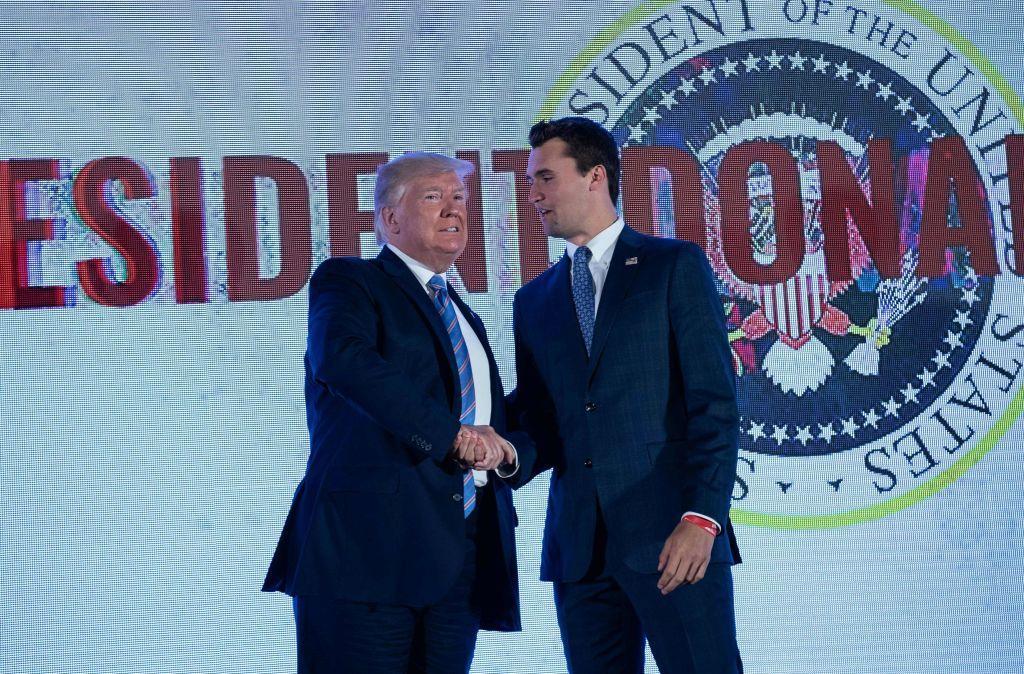 Donald Trump dándole la mano a Charlie Kirk.