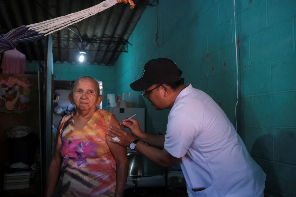 Un trabajador de la salud administra una vacuna contra el sarampión a una mujer en el barrio Emmanuel como parte de una campaña de vacunación en Mejicanos, El Salvador, el 13 de abril de 2026. REUTERS/Jose Cabezas