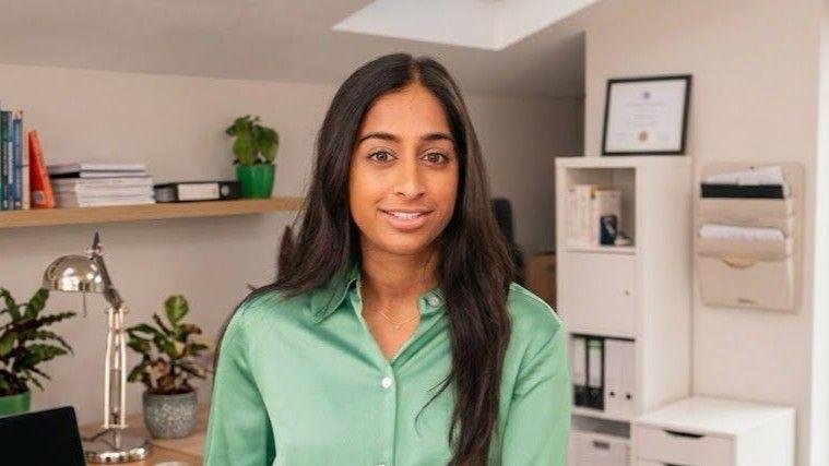 Anjali Malik has long black hair and wears a green shirt