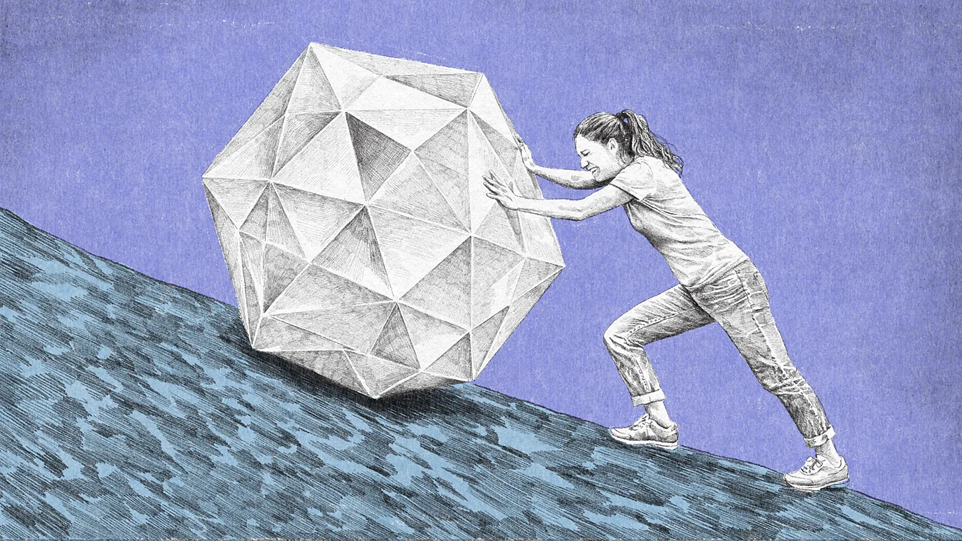 一名女子在斜坡向上推著個一塊多邊形物體