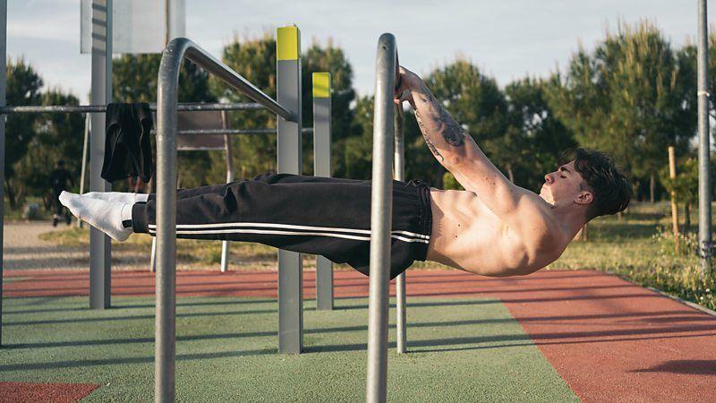 Homem fazendo exerc&iacute;cio em academia ao ar livre
