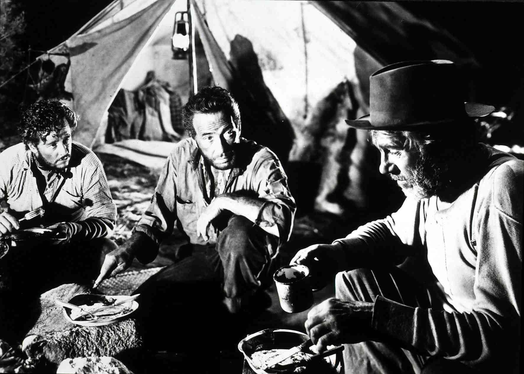 Tim Holt, Humphrey Bogart y Walter Houston frente a una carpa, comiendo a la intemperie,  en una escena de "El Tesoro de la Sierra Madre".