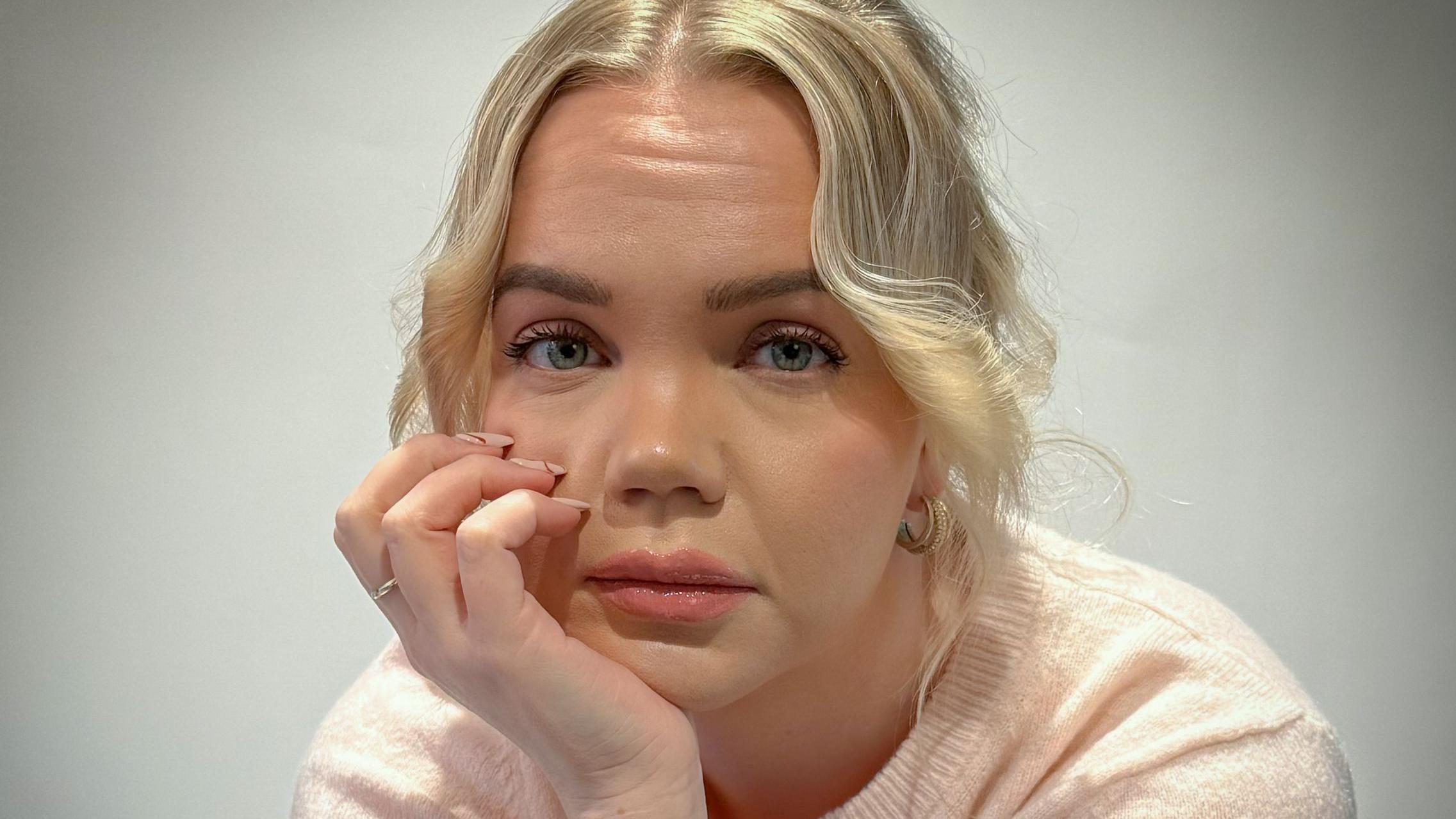 Meri-Tuuli Auer mirando a la cámara mientras está sentada y apoya su cabeza en una de sus manos.