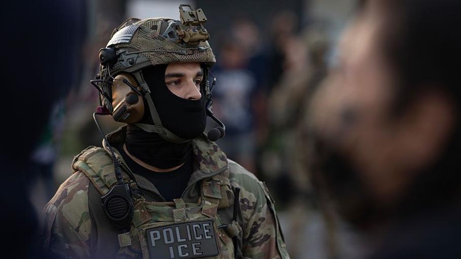 Agente de ICE con uniforme de camuflaje y la cara parcialmente tapada