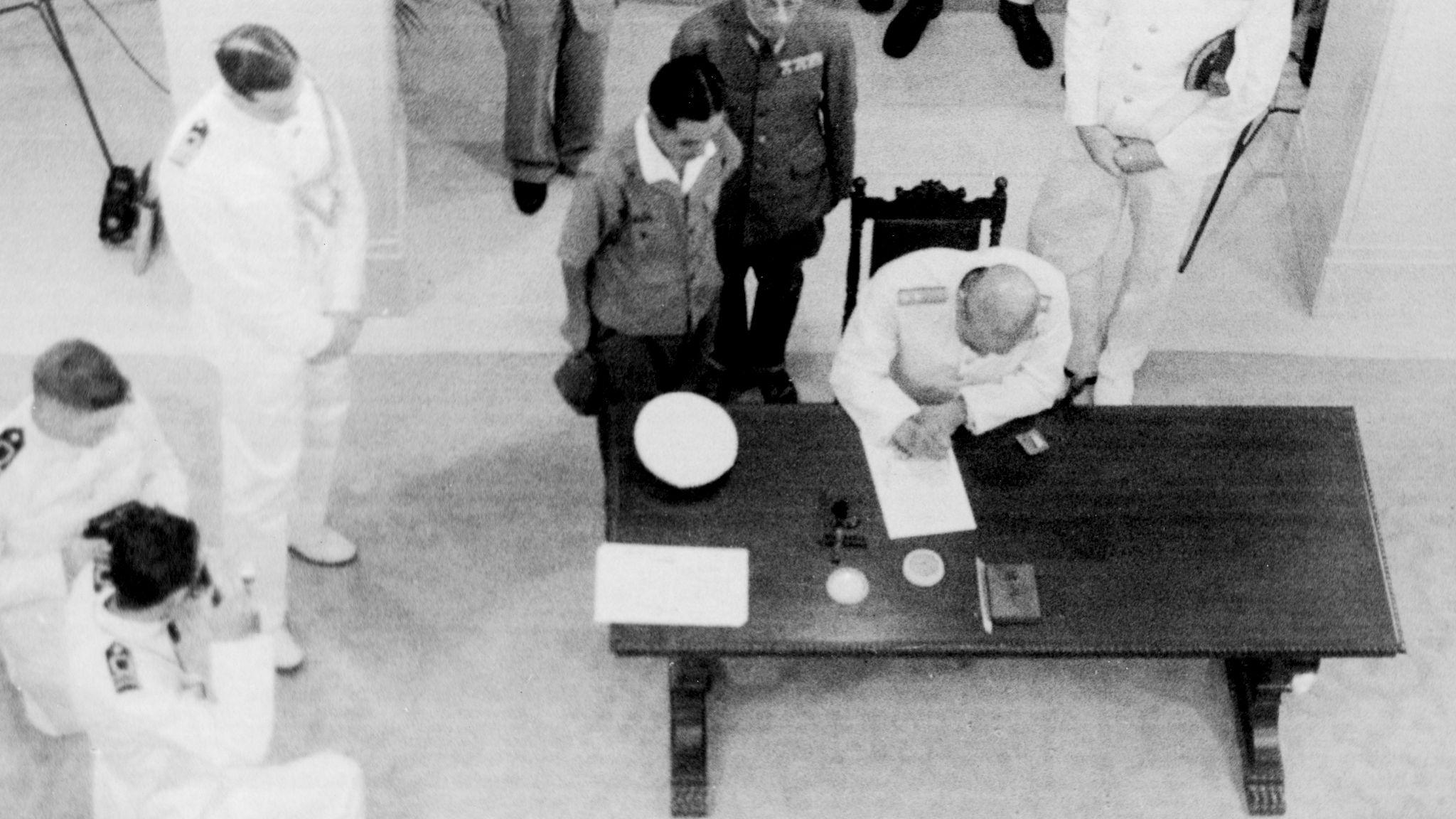 日本海軍中將藤田類太郎（桌前者）在香港總督府簽署降書（16/9/1945）
