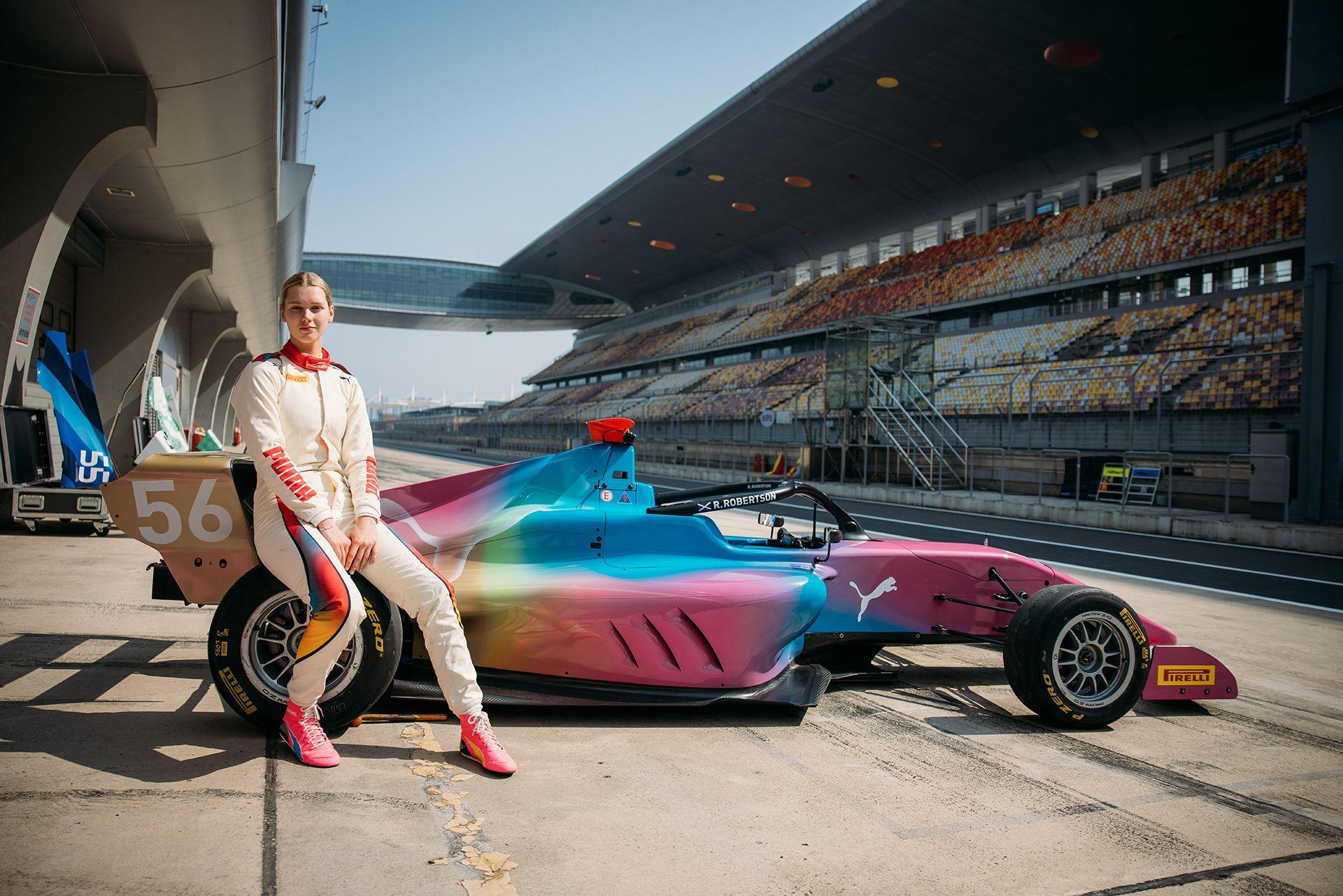 Rachel Robertson, sentada sobre um carro da F1 Academy em uma pista de corrida