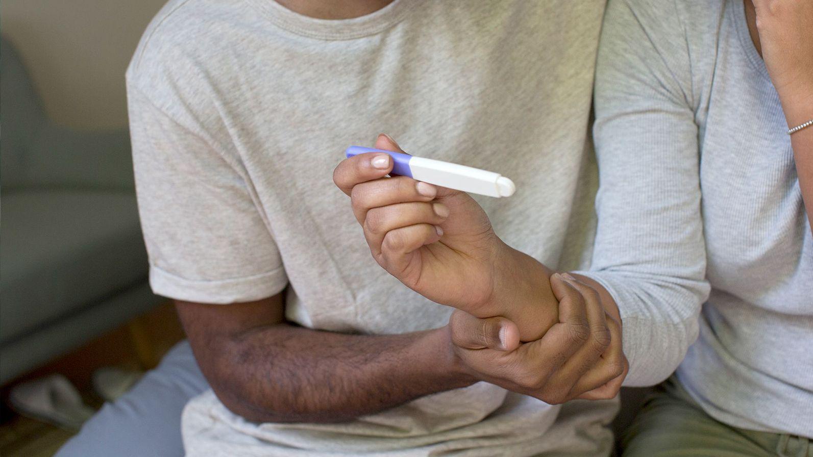 Una pareja mira el resultado de un test de embarazo. 