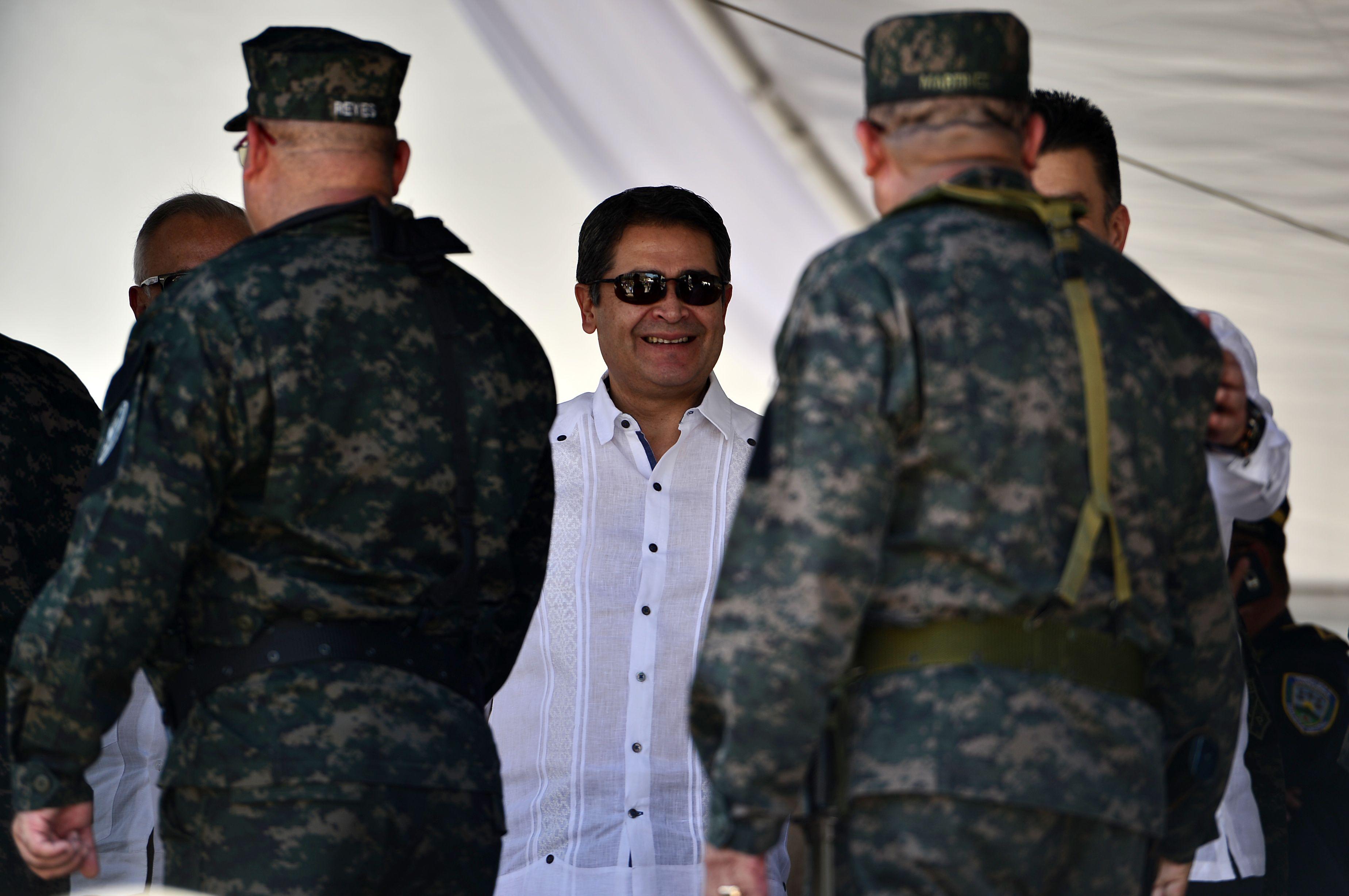 Juan Orlando Hernández sonríe frente a militares siendo presidente de Honduras en 2019.