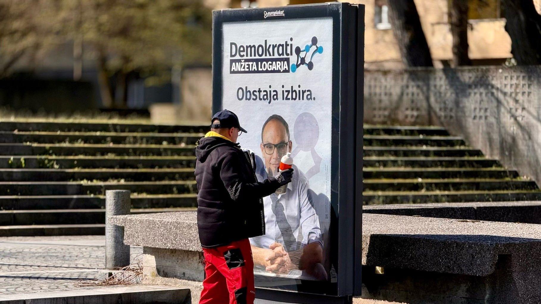 Čovek čisti bilbord sa pozivom na glasanje Demokratske partije