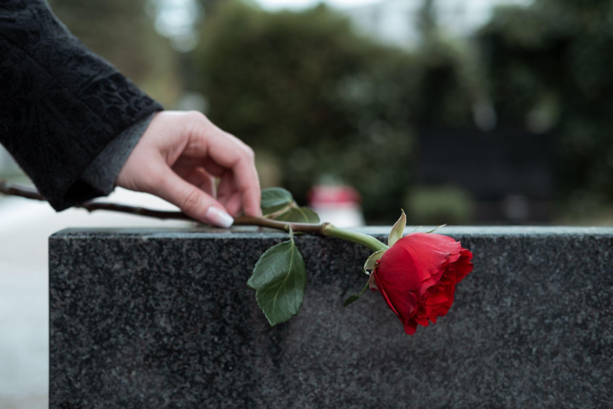 Una mujer coloca una flor sobre una tumba