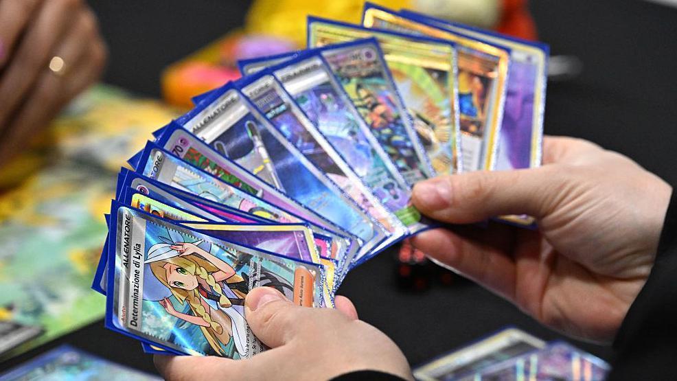 Un competidor sostiene un mazo que muestra una carta de Determinación Lylia mientras juega al Juego de Cartas Coleccionables Pokémon durante el Campeonato Internacional Pokémon Europa