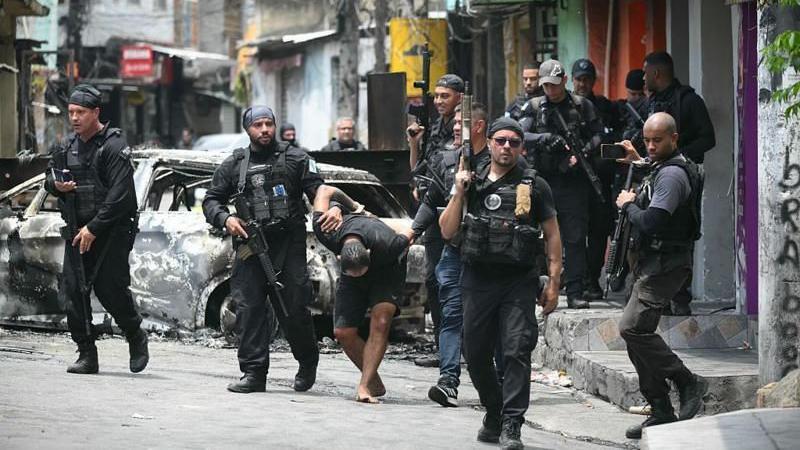 Policiais escoltam um suspeito preso durante a Operação Contenção na favela da Vila Cruzeiro, no complexo da Penha, no Rio de Janeiro, Brasil, em 28 de outubro de 2025 