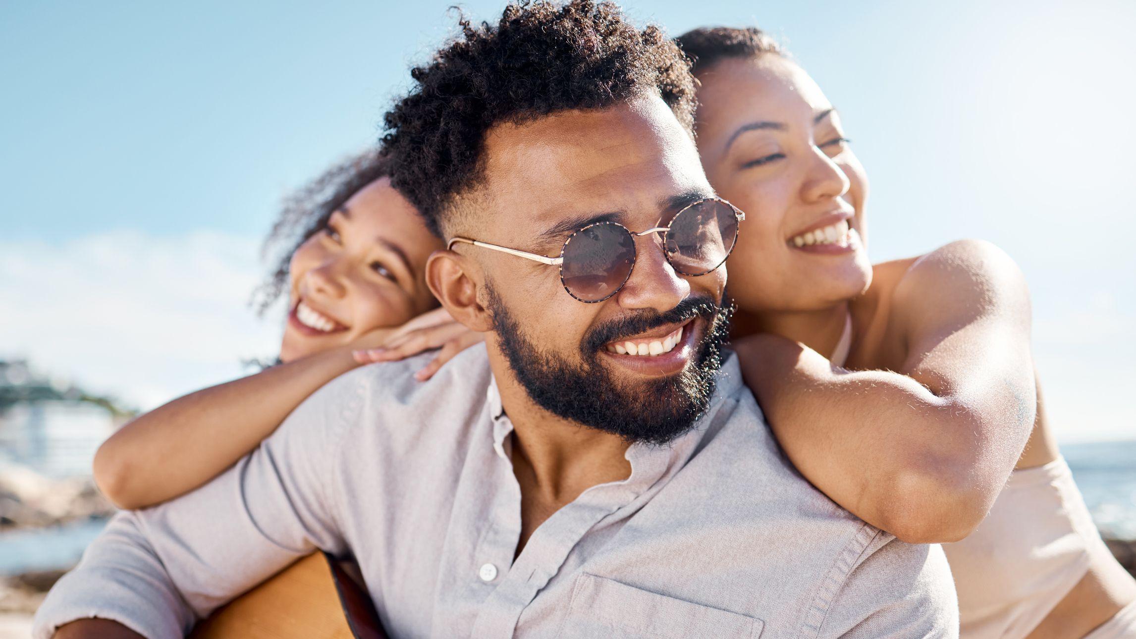 Fotografía de un hombre en la playa con dos amigas.