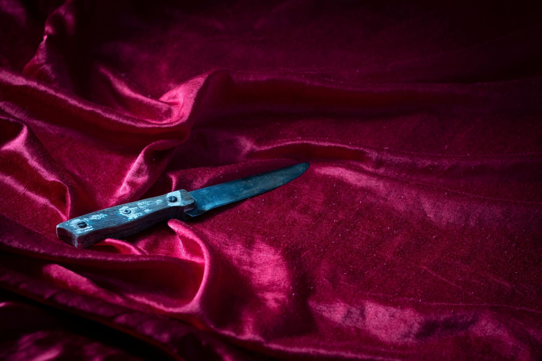 Grande faca sobre roupa de cama rosa e cintilante