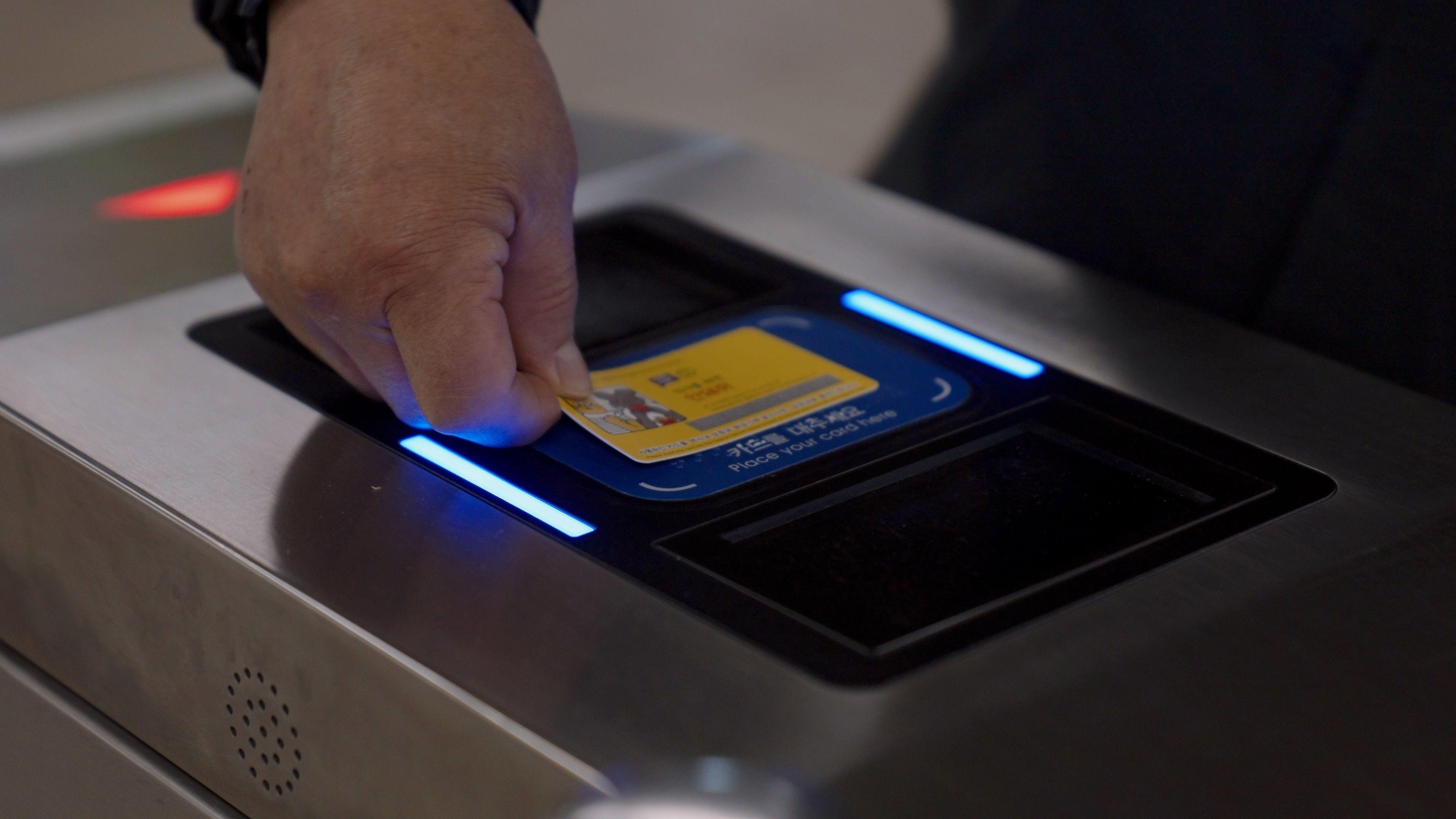 지하철 개찰구에서 한 이용자가 교통카드 단말기에 카드를 찍고 통과하고 있다