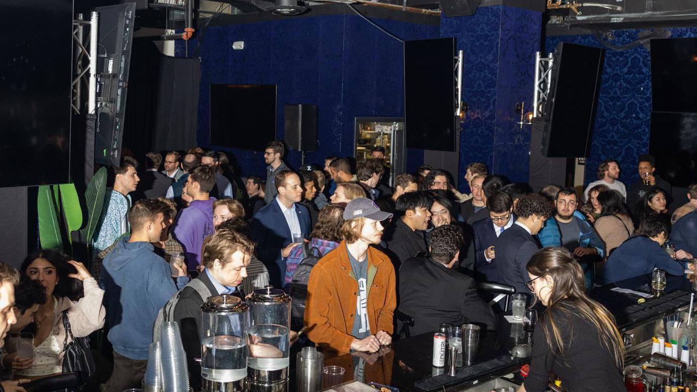 Fila para entrar no bar em um ambiente escuro. A maioria dos clientes &eacute; formada por homens jovens