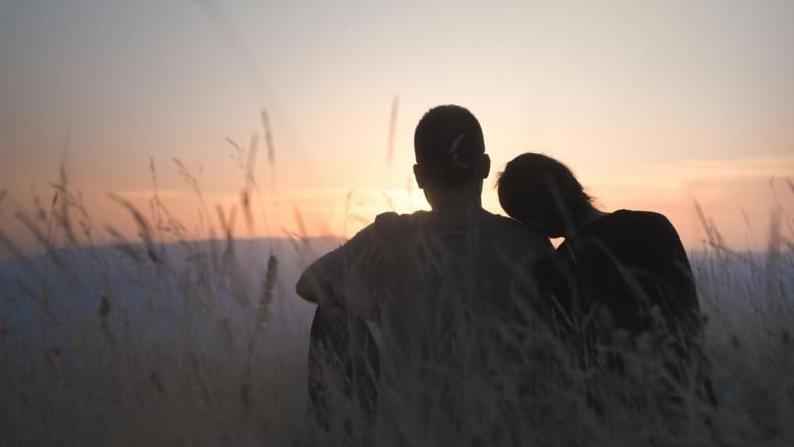 Pareja sentada a contraluz en la naturaleza. 