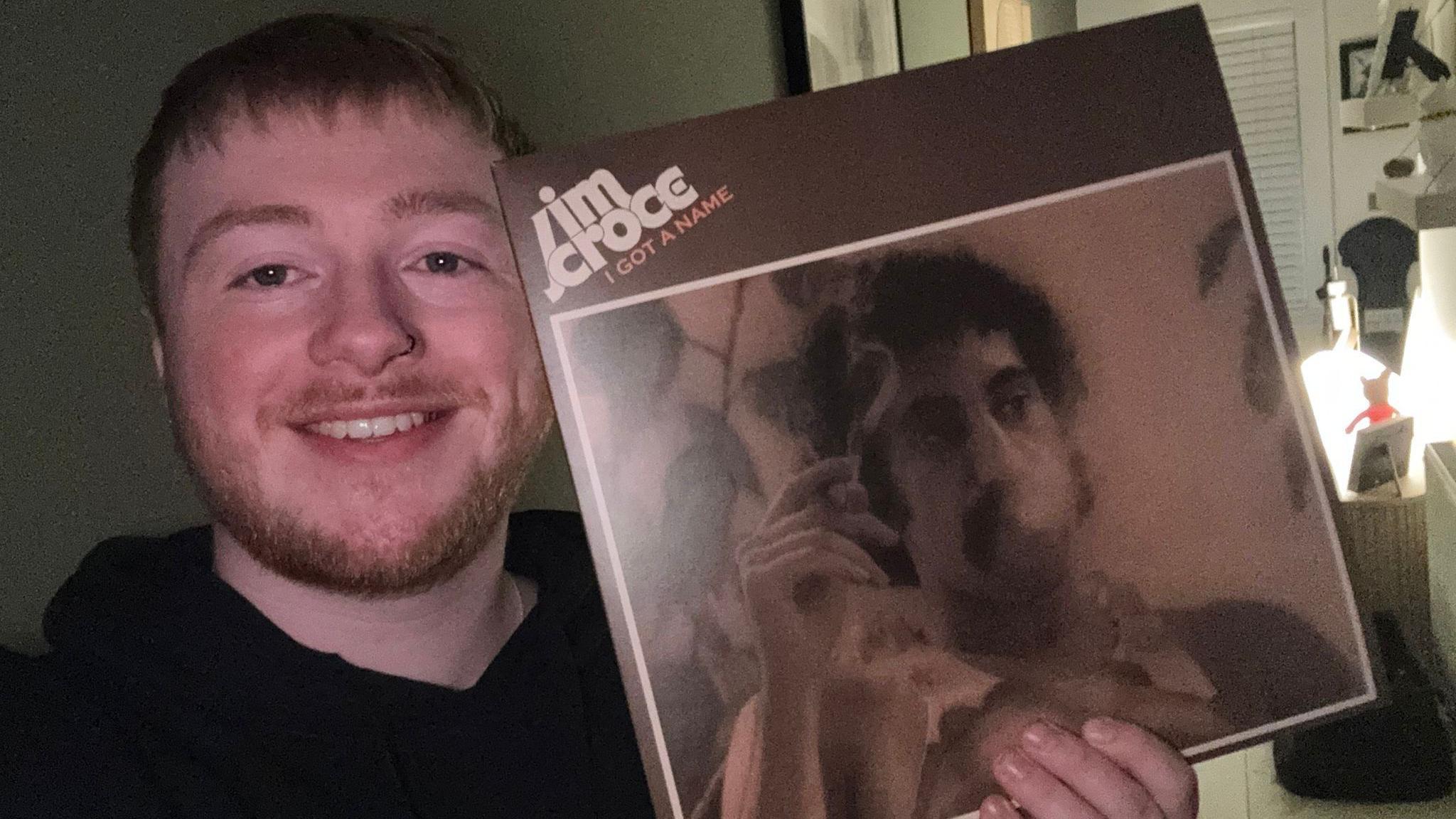 索爾穿著黑色連帽外套，手中拿著兩張黑膠唱片。背景是一面綠色牆壁，上面掛有裝裱的藝術作品和一面圓形鏡子