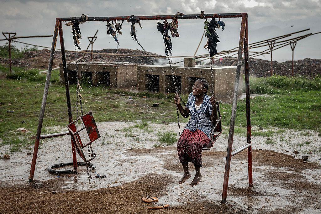 Una joven refugiada congoleña juega en un columpio bajo una fuerte lluvia mientras los refugiados esperan ser reubicados en el Centro de Tránsito de Cishemere, cerca de Buganda, el 6 de mayo de 2025.