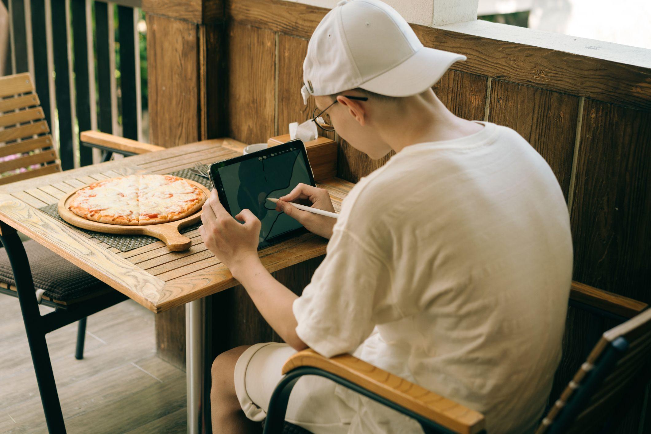 Un joven está sentado en una mesa con una tableta con la columna doblada.