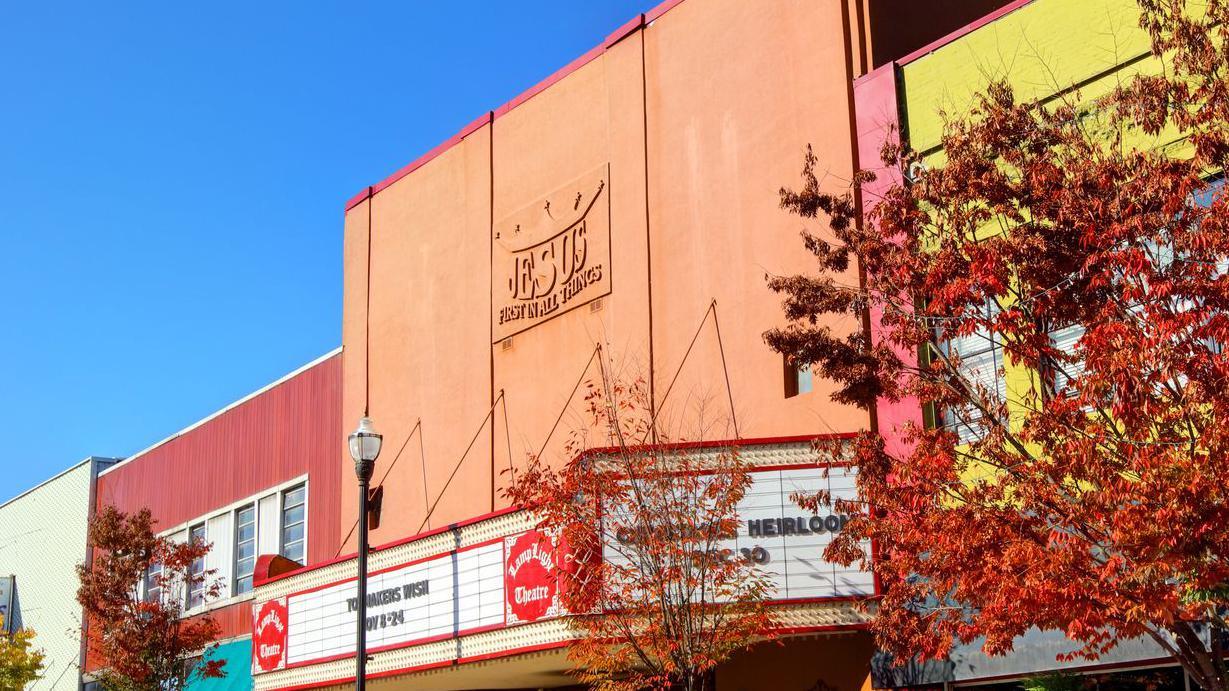 El teatro Lamplight, en una calle central con una calzada con árboles pequeños y lámparas, tiene un letrero sobre su fachada color ladrillo que lee: "Jesús sobre todas las cosas"
